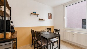 A dining area with a table and chairs, a coffee machine, and a window with a view. - Seibels Suites - Ruhrpott Oasis Altenessen (Essen)