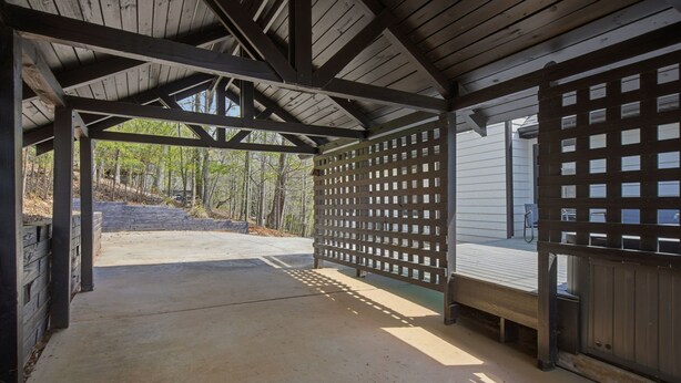 A covered outdoor area with a concrete floor, wooden beams, and a lattice fence. - Beautiful 5-bedroom lodge in Jasper Georgia (Big Canoe)