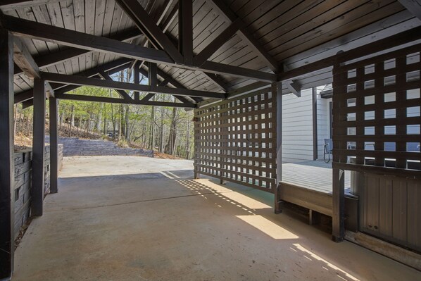 A covered outdoor area with a concrete floor, wooden beams, and a lattice fence.