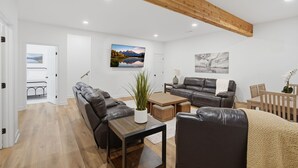 A modern living room with a sofa, a coffee table, and a TV mounted on the wall. - Beautiful 5-bedroom lodge in Jasper Georgia (Big Canoe)