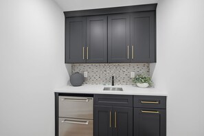 A kitchen with dark cabinets, a stainless steel dishwasher, and a tiled backsplash.