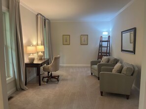 Una habitación con un escritorio, dos sillas, una escalera y dos cuadros en la pared.