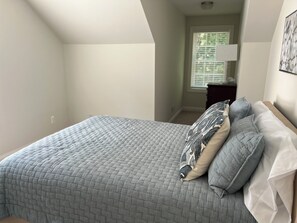 Un dormitorio con cama, almohadas y mesita de noche.