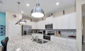 A kitchen with white cabinets, stainless steel appliances, a granite countertop, and pendant lighting. - Go!#24 - WINDSOR ISLAND (Davenport)