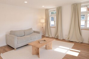 Una sala de estar moderna con un sofá, una mesa de centro de madera y una lámpara de pie.