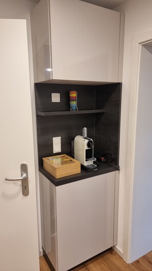 Pieni, käytännöllinen keittiönurkkaus, jossa on mikroaaltouuni, kahvinkeitin ja pieni puinen rasia.
