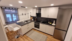 A modern kitchen with a central island, built-in oven, and stainless steel appliances.