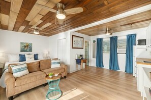 A living room with a sofa, a coffee table, and a dining area with a table and chairs. - Birdwatch Bungalow Upstairs (Cedar Key)