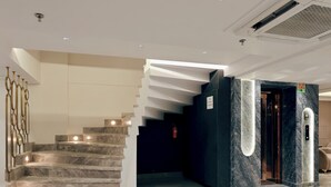 A modern interior with a marble staircase, a fire hydrant, and a sign indicating a fire hydrant chamber. - Hotel The Janak by Shanti (New Delhi)