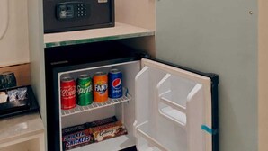 A compact minibar with a beverage cooler, a small refrigerator with snacks, and a hanging coat rack. - Hotel The Janak by Shanti (New Delhi)