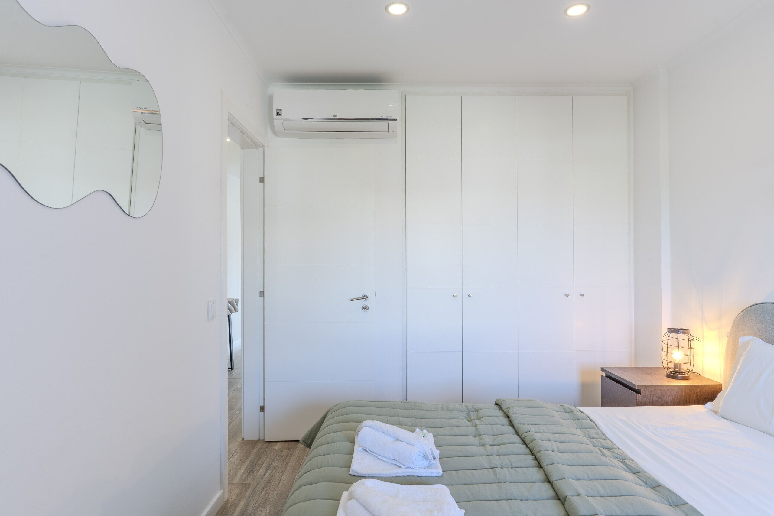 A bedroom with a bed, a nightstand, a lamp, and a wardrobe.
