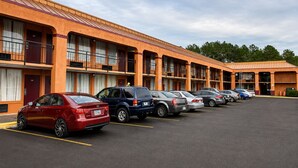 A motel with multiple rooms, a parking lot, and a clear sky. - Studio Lodge of Macon (Macon)
