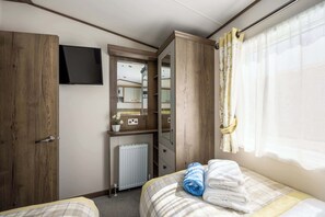 A bedroom with a bed, a wardrobe, a mirror, a radiator, and a TV mounted on the wall.