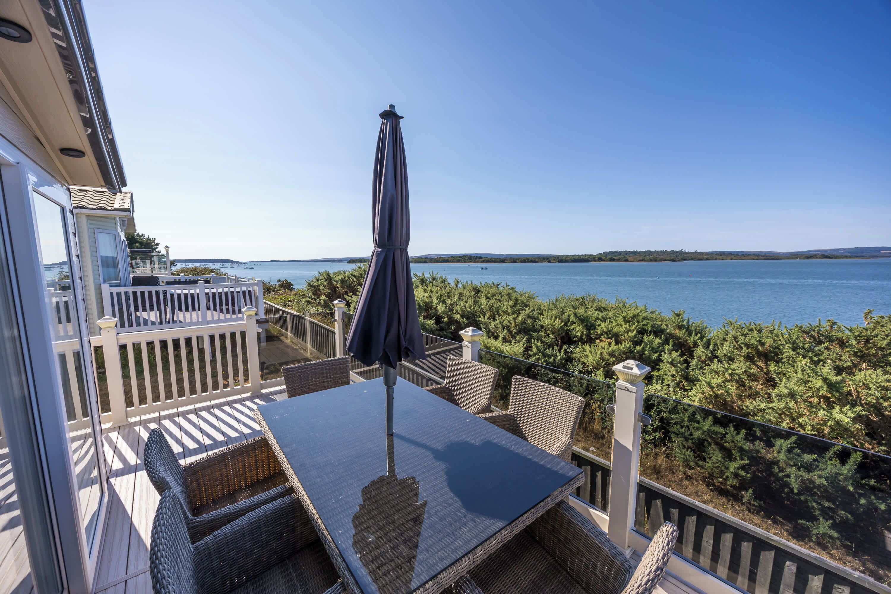En balkon med et bord og stole, med udsigt over vandet.