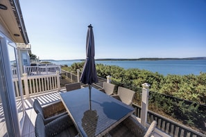 Uma varanda com mesa e cadeiras, com vista para a água.