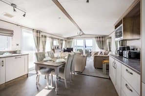 Interior moderno com área de jantar, sofá, cozinha e amplas janelas com vista.