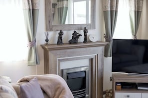A living room with a fireplace, a television, and decorative statues.