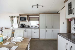 A compact kitchen with a dining area, including a table set for two, a microwave, and cabinets.