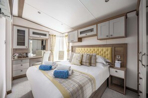 Quarto de hotel com uma cama grande, uma mesa de cabeceira, um guarda-roupa e um banheiro visível por uma porta aberta.