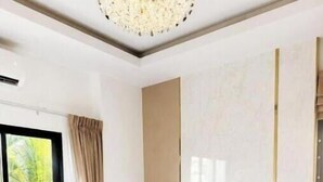 A bedroom with a large bed, a nightstand, a lamp, and a window with curtains. - Paradise Away From Home | Elegant Lakeview Villa with Pool in Central Pattaya (Chon Buri)