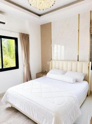 A bedroom with a large bed, a nightstand, a lamp, and a window with curtains. - Paradise Away From Home | Elegant Lakeview Villa with Pool in Central Pattaya (Chon Buri)