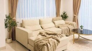 A modern living room with a beige sofa, a coffee table, and curtains. - Paradise Away From Home | Elegant Lakeview Villa with Pool in Central Pattaya (Chon Buri)
