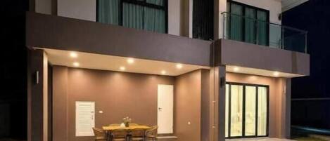 A modern two-story house with a dining area and a balcony.