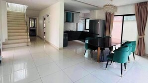A spacious living area with a dining table and chairs, a staircase, and a kitchen area. - Paradise Away From Home | Elegant Lakeview Villa with Pool in Central Pattaya (Chon Buri)