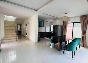 A spacious living area with a dining table and chairs, a staircase, and a kitchen area. - Paradise Away From Home | Elegant Lakeview Villa with Pool in Central Pattaya (Chon Buri)