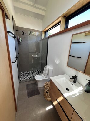 Une petite salle de bain comprenant une douche, des toilettes et un lavabo.