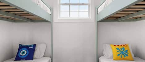 A room with two bunk beds, a window, and a small wall-mounted shelf.