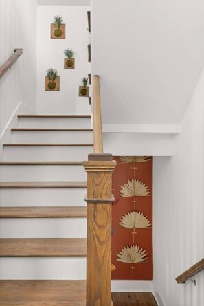 Eine Treppe mit Holzboden und Holzhandlauf, die zu einer Empore mit roter Wand und dekorativen Blattmustern führt.
