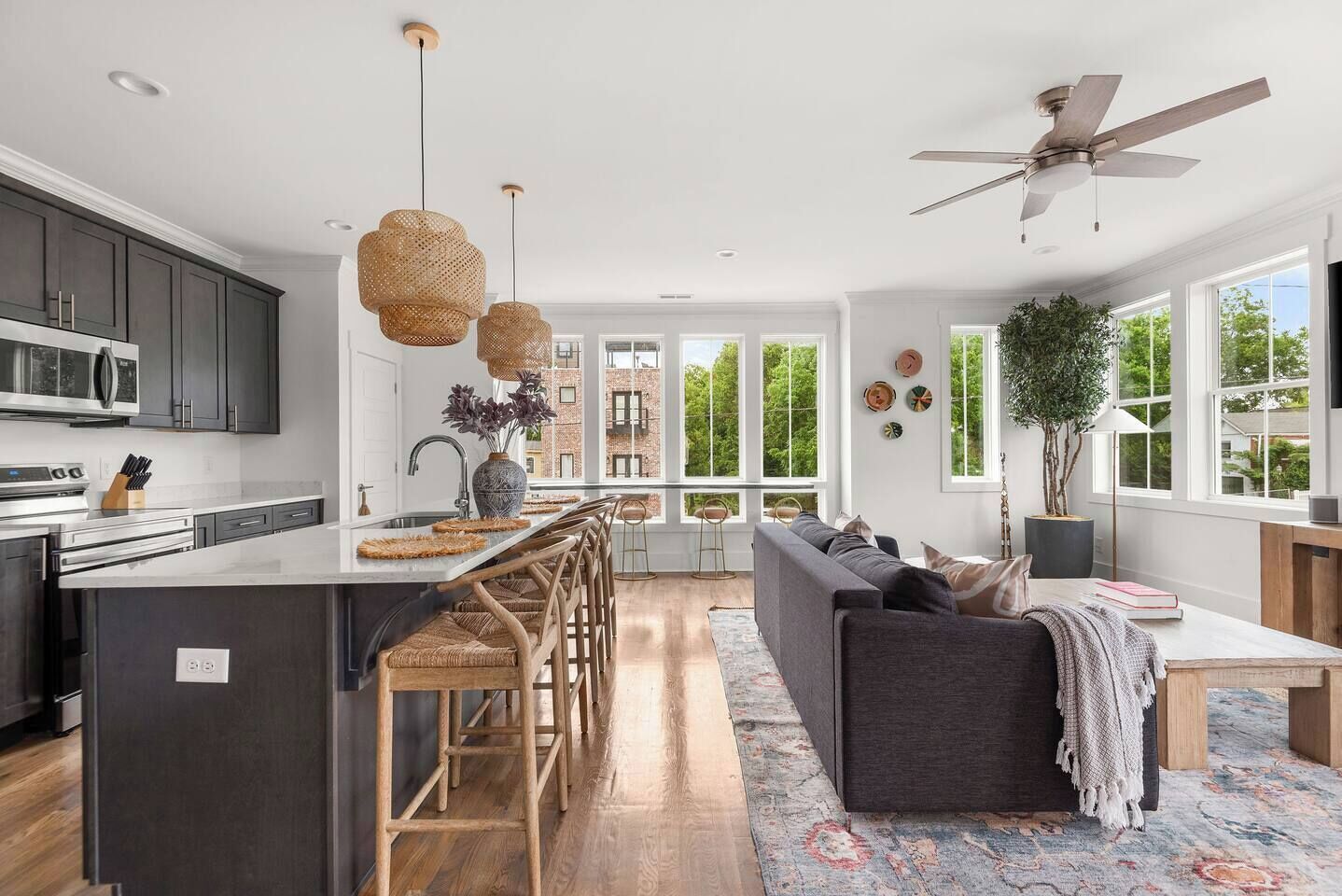 A modern kitchen with a central island, dark cabinetry, and a dining area with a sofa and chairs.