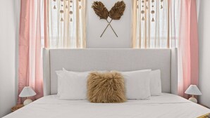 Ein Bett mit weißer Bettwäsche, einem flauschigen Kopfkissen und einer dekorativen Wandgestaltung.