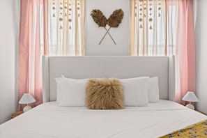 A bed with white bedding, a fluffy pillow, and a decorative wall piece. - Soak it up in East! 8 beds 3.5 bath Garage incl! (Nashville)
