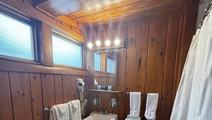 A bathroom with wooden walls, a white sink, a toilet, and a shower curtain. - Cozy 1BR hotel room, Hamilton - #341 Rode-A-Syde (Hamilton)