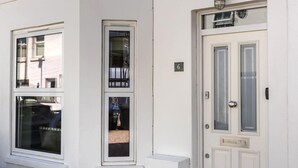 Ein weißes Gebäude mit einer nummerierten Tür und zwei Fenstern.