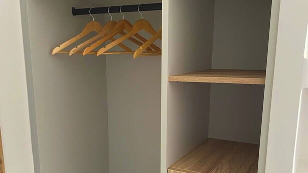A walk-in closet with wooden hangers, a wooden shelf, and a drawer unit. - SEAL of Knight - Castle View - Downtown near the Beach (Rodos)