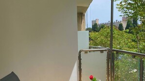 A balcony with a glass table, a chair, and a decorative vase with a rose. - SEAL of Knight - Castle View - Downtown near the Beach (Rodos)