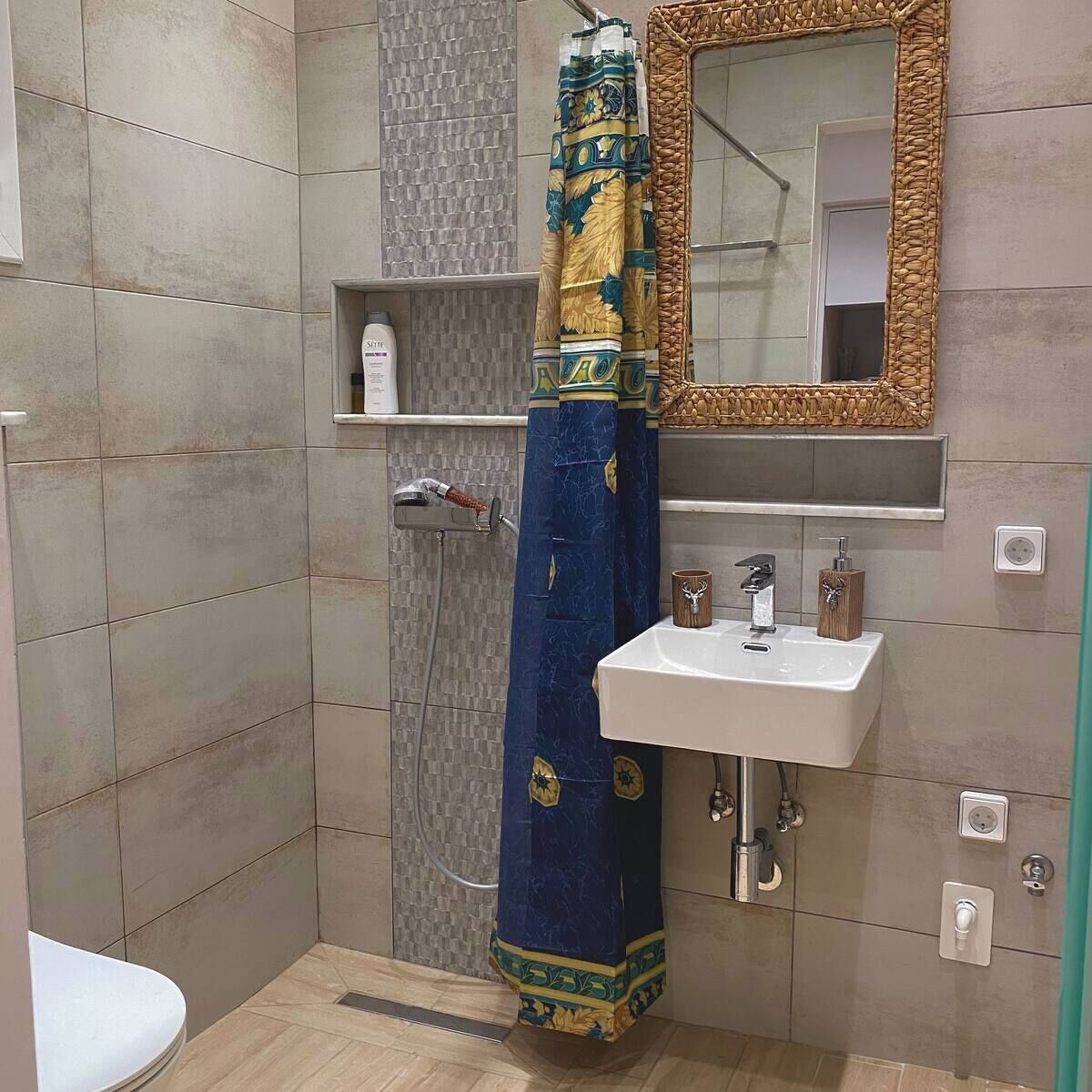 Un baño con ducha, lavamanos, espejo y toallero.