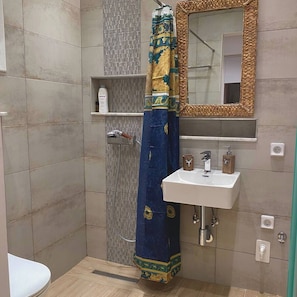 Ein Badezimmer mit Dusche, Waschbecken, Spiegel und Handtuchhalter.