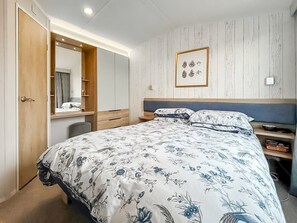 Ein Schlafzimmer mit Bett, Nachttisch, Spiegel und Kleiderschrank.