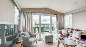 A furnished room with a sofa, armchair, and a small table. - St Andrews Holiday Park | Swilken Sanctuary No 17 (St Andrews)