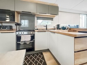Eine Küche mit Herd, Backofen, Mikrowelle und einem Fenster.