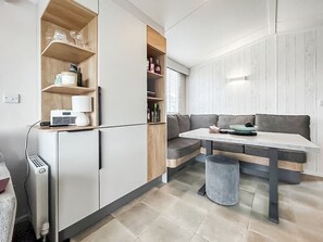 Eine kompakte Küche mit eingebauten Geräten, eine Sitzecke mit einer Bank und ein kleiner Mülleimer.