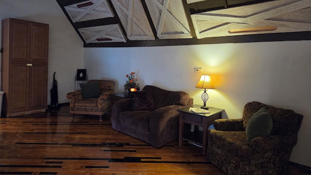 A room with a wooden floor, a sofa, a chair, a lamp, and a wooden cabinet. - Charming Loft near Cleveland, TN to relax and rewind in. (Cleveland)