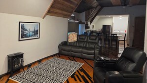 A living room with a black leather sofa, a black leather chair, a patterned rug, and a framed picture on the wall. - Charming Loft near Cleveland, TN to relax and rewind in. (Cleveland)