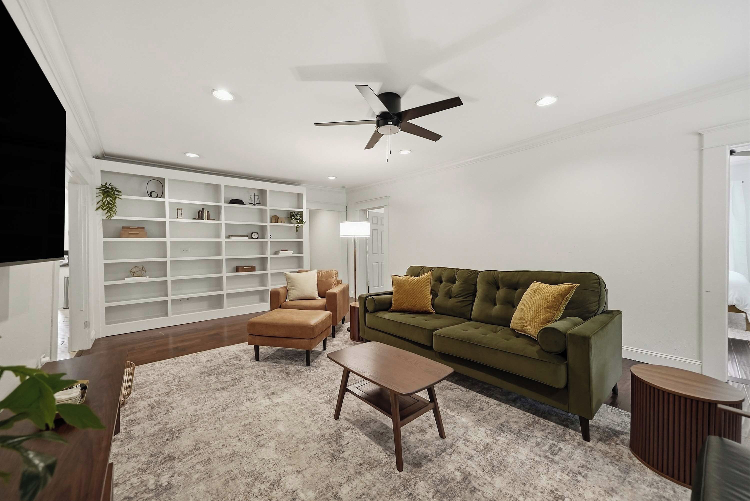 A modern living room with a green sofa, a brown armchair, and a wooden coffee table.