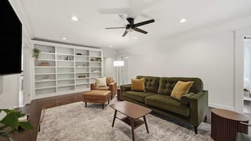 A modern living room with a green sofa, a brown armchair, and a wooden coffee table.