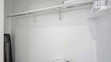A white closet with a metal rod for hanging clothes and a white plastic basket.